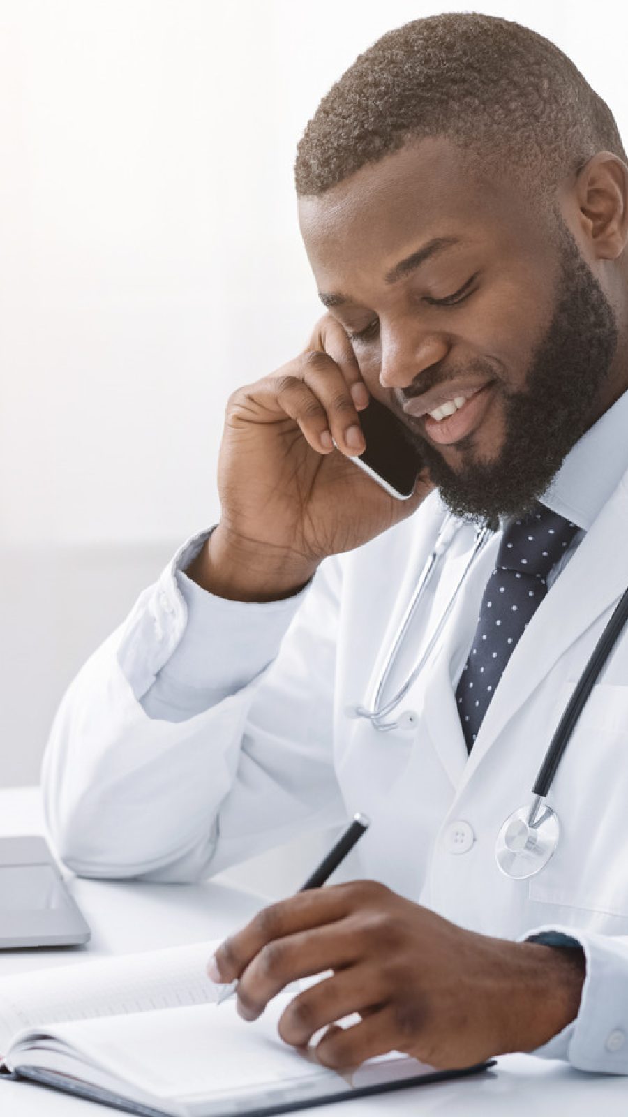 Young,African,Doctor,Talking,To,Patient,On,Phone,While,Working